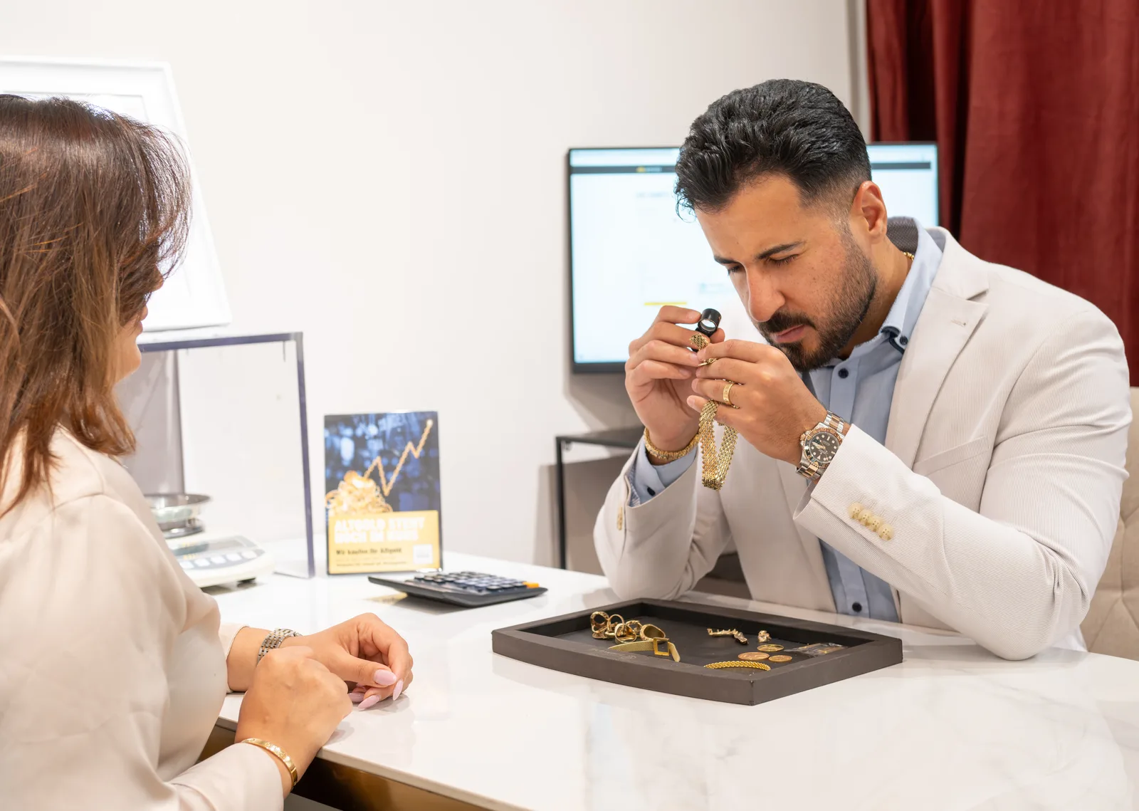 Sameer Alhamd prüft Schmuck mit der Lupe am Beratungstisch bei RT Goldrausch Reutlingen