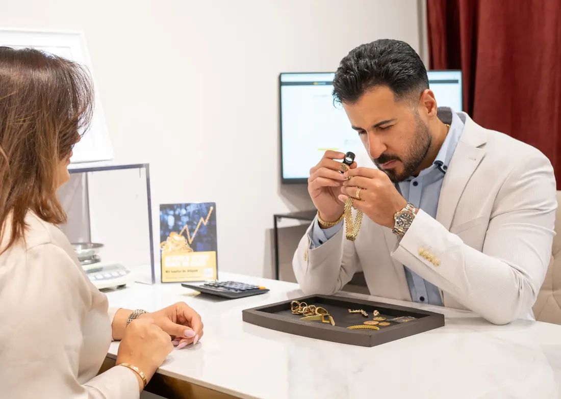 Inhaber von RT Goldrausch prüft Goldschmuck einer Kundin am Beratungstisch